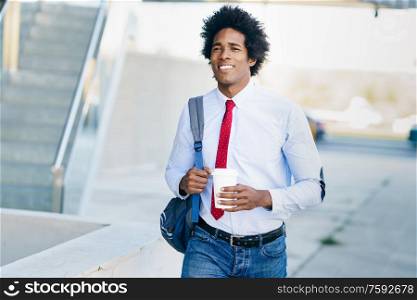 Black Businessman walking down the street with a take-away glass. Man with afro hair.. Smiling Black Businessman with a take-away glass.