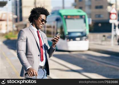 Black Businessman wearing suit waiting his train on an outdoors station. Man with afro hair.. Black Businessman wearing suit waiting his train