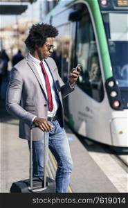 Black Businessman wearing suit waiting his train on an outdoors station. Man with afro hair.. Black Businessman wearing suit waiting his train
