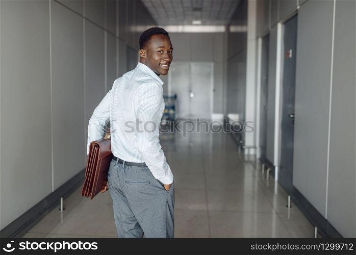 Black businessman with briefcase in office hall. Successful business person walking down the corridor, black man in formal wear. Black businessman with briefcase in office hall