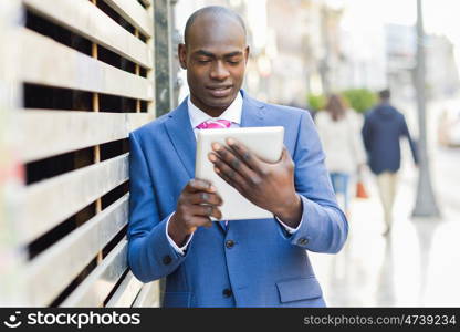 Black businessman with tablet computer in urban background