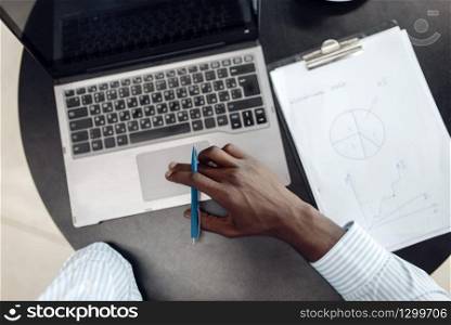 Black businessman working on laptop in office, top view. Successful business person at his workplace, black man in formal wear. Black businessman working on laptop, top view
