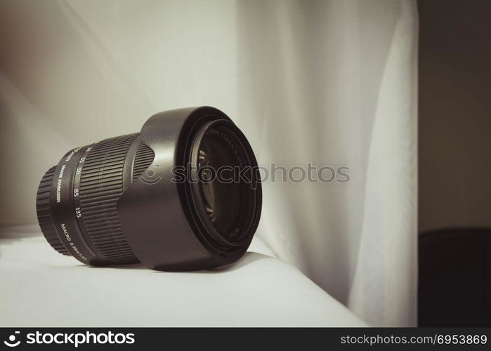 Black camera zoom lens on white cloth.