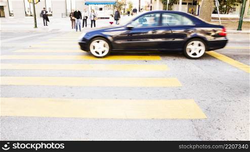 black car driving road with yellow zebra crossing