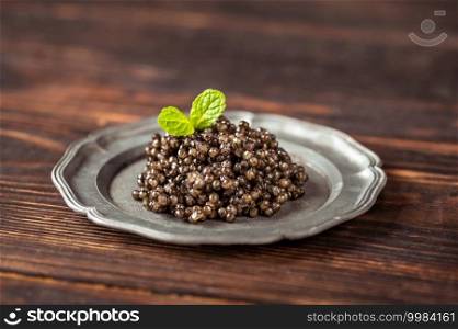 Black caviar on silver vintage plate close-up