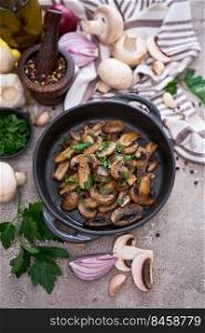 black ceramic bowl with fried mushrooms on grey concrete background.. black ceramic bowl with fried mushrooms on grey concrete background