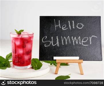 black chalk board for writing a summer drink recipe and a glass with berry lemonade, inscription hello summer