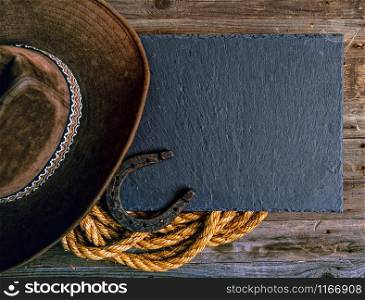 Black chalk board lasso horseshoe and traditional cowboy hat on wooden background. western cowboy background