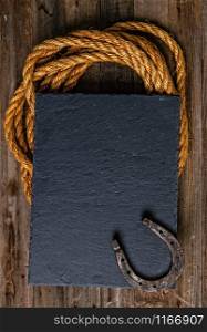 Black chalk board with horseshoe and lasso on wooden background. western cowboy background