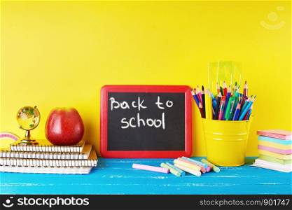 black chalk frame, chalks and school supplies on a blue background, concept back to school