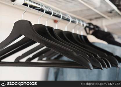 Black clothes hangers on a rack in a clothing store, close-up, selective focus. Fashion, clearance sale in the store. Blog banner