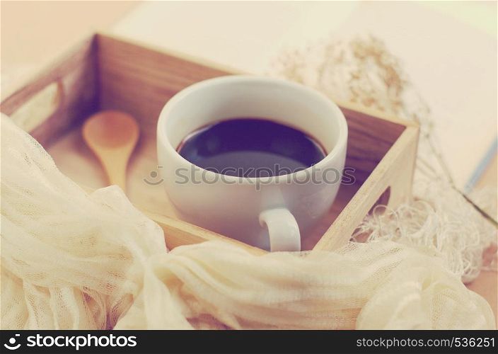 Black coffee and spoon on wooden tray, retro filter effect