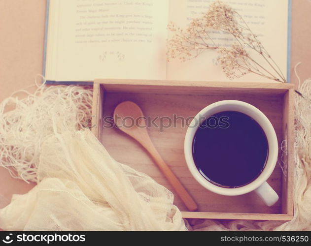 Black coffee and spoon on wooden tray with book, retro filter effect