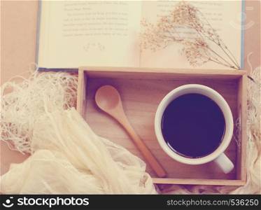 Black coffee and spoon on wooden tray with book, retro filter effect