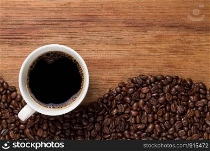 black coffee bean and white cup, brown wood table