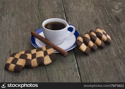 black coffee in a saucer with a blue border and checkered cookies