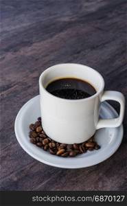 Black Coffee in a white cup set and coffee been on the gray wooden table with copy space
