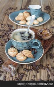 Black coffee in blue ancient cup and biscuit cookies on old dark cutting board