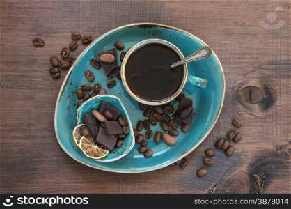 Black coffee in blue vintage cup and chocolate on a old dark wooden boards