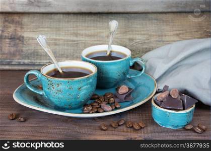 Black coffee in blue vintage cups, cookies and chocolate on a old dark wooden boards