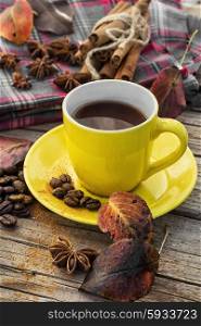 Black coffee in yellow cup. Coffee in yellow mugs with spices on background of warm blanket in one in autumn weather.