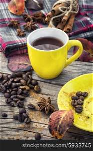Black coffee in yellow cup. Coffee in yellow mugs with spices on background of warm blanket in one in autumn weather.