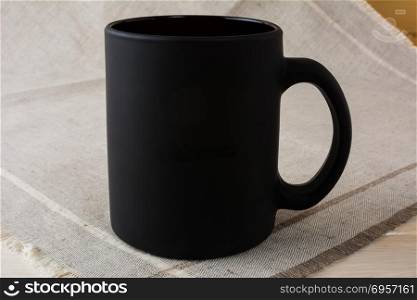 Black coffee mug mockup on the linen napkin. Black coffee mug mockup on the linen napkin. Empty mug mockup for product presentation. Coffee cup mock-up for promotion brand or design.
