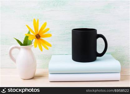 Black coffee mug mockup with yellow rosinweed flowers in pitcher. Empty mug mock up for brand promotion.. Black coffee mug mockup with yellow rosinweed flowers in pitcher