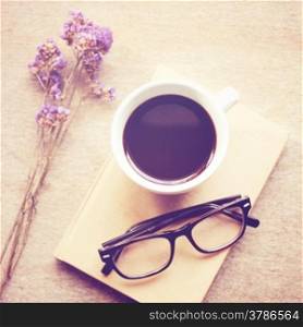 Black coffee on notebook with eyeglasses, retro filter effect