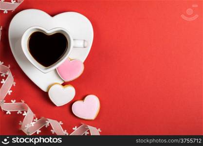 Black coffee with cookies in shape of heart on red paper background. Composition for Valentines Day. Top view. Empty room for text