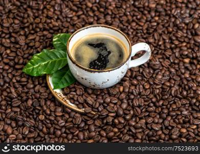Black coffee with green leaves on caffee beans background. Food und drinks