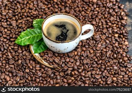 Black coffee with green leaves on coffee beans background. Food und drinks