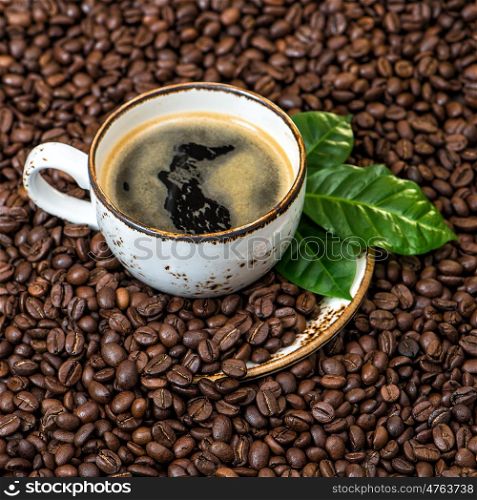Black coffee with green leaves on coffee beans background square