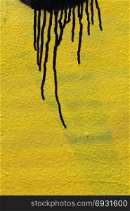 Black color dripping on yellow paint smudged wall background. Abstract artistic texture.