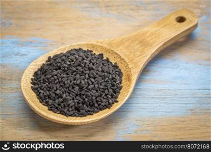 black cumin seeds (Nigella sativa) on a wooden spoon