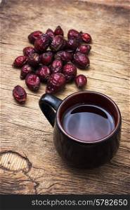 black cup medicinal tea on the background of scattered dried rose hips. tea brewed with rose hips