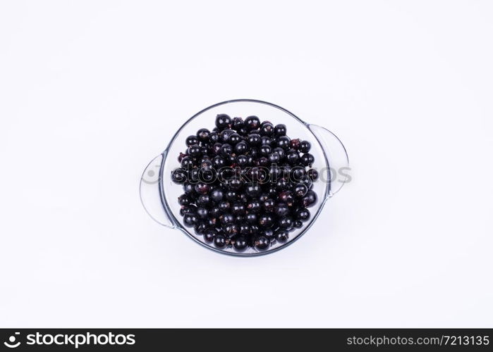 black currants in a transparent, glass bowl on a white background, top view. black currant