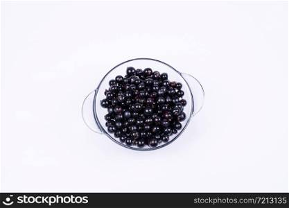 black currants in a transparent, glass bowl on a white background, top view. black currant