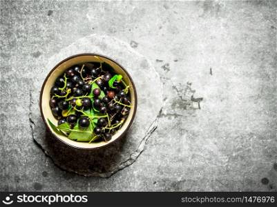 Black currants with leaves in the Cup. On the stone table.. Black currants with leaves in the Cup.