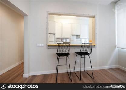 black designer chairs placed in the hole in the kitchen wall with a counter for breakfast or lunch.