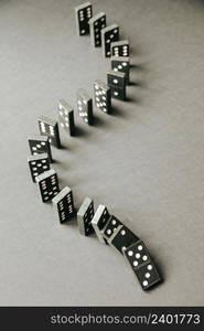 Black dominoes chain on a table background. Domino effect concept. Black dominoes chain on table background