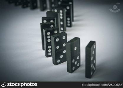 Black dominoes chain on a table background. Domino effect concept. Black dominoes chain on table background