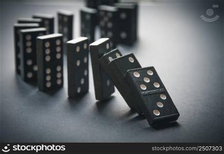 Black dominoes chain on a table background. Domino effect concept. Black dominoes chain on table background