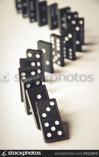 Black dominoes chain on a white table background. Domino effect concept. Black dominoes chain on white table background