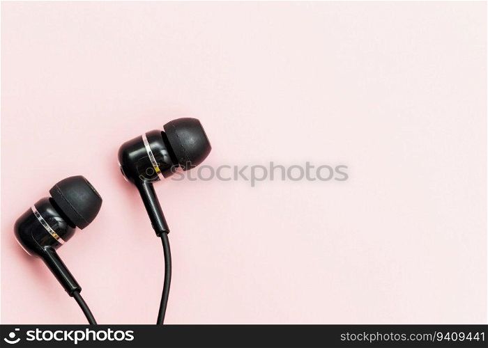 Black earphones on pink background for audio listening concept