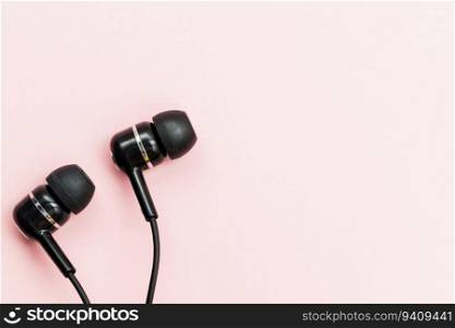 Black earphones on pink background for audio listening concept
