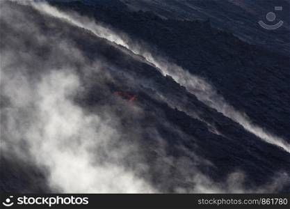 Black earth on volcano Stromboli with fire and steam