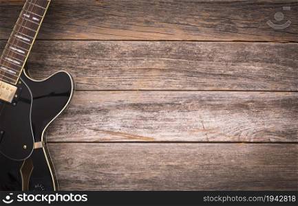 Black electric guitar on a rustic wooden background