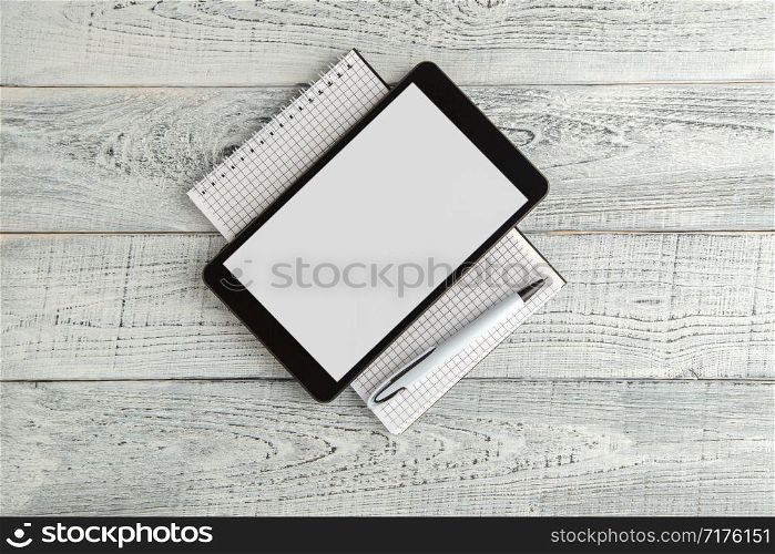 black electronic tablet and paper notebook on vintage shabby white wooden background. the view from the top. flat lay