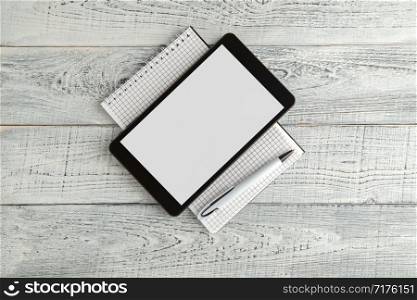 black electronic tablet and paper notebook on vintage shabby white wooden background. the view from the top. flat lay
